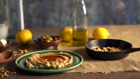 Warm,-low-angle-slide-to-the-right-showing-middle-eastern-food-spread-of-olives,-pine-nuts,-hummus,-feta-and-ouzo