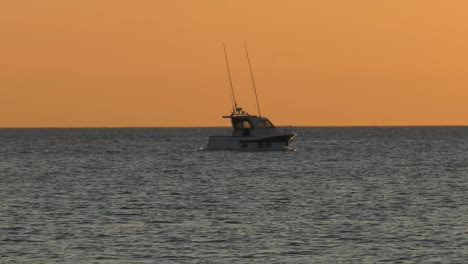 Motor-boat-on-calm-sea-sailing-to-horizon-at-dawn