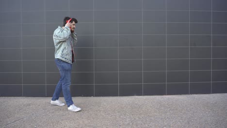 man-puts-on-red-headphones-and-walks-while-looking-at-red-cell-phone