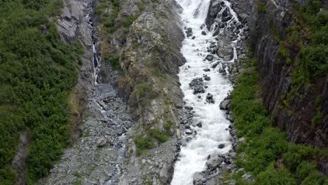 Luftaufnahme-Des-Schnellen-Bachwassers,-Das-Die-Felsigen-Hügel-Alaskas-Hinunterfällt