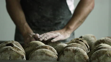 Baker-Arranging-The-Sourdough-Breads-On-A-Baking-Rack-In-A-Bakery