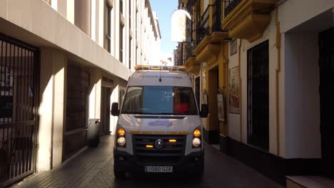 Ambulance-backing-up-driving-backward-on-narrow-Spanish-alley,-Static