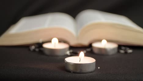Three-tea-light-candles-with-open-book-background-medium-shot