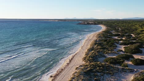 Trench-Beach-at-the-southern-edge-of-Mallorca-Island-in-Spain-with-people-walking-on-sand,-Aerial-flyover-reveal-shot