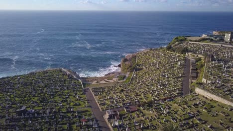 Graveyards-on-the-cliff-with-spectacular-Pacific-Ocean-view,-aerial-forward-flying-over-most-popular-coastal-walk-at-Waverley-cemetery-in-Sydney-Eastern-Suburb,-Australia