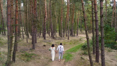 Newlywed-couple-walking-barefoot-on-a-forest-road,throwing-the-bouquet