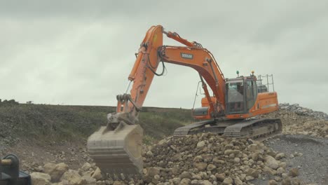 Digger-excavator-moving-stone-around-with-old-worn-bucket-attachment