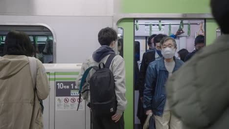 Local-Passengers-In-Face-Mask-Getting-Off-The-Train-On-The-Subway-Station-During-Covid19-Pandemic-In-Tokyo,-Japan