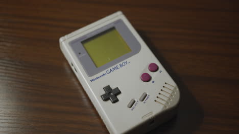 Panning-Close-Up-of-the-Original-Nintendo-Game-Boy-on-a-Wooden-Table