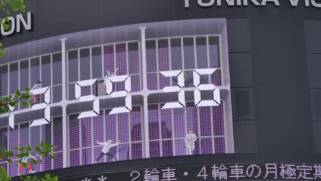 Sehr-Lustige-Riesige-Digitaluhr-An-Der-Seite-Eines-Gebäudes-In-Tokio,-Japan