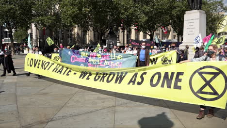 Extinction-Rebellion-climate-change-protestors-gather-on-Trafalgar-Square-behind-a-yellow-banner-that-reads,-“Love-not-hate---we-grow-as-one”