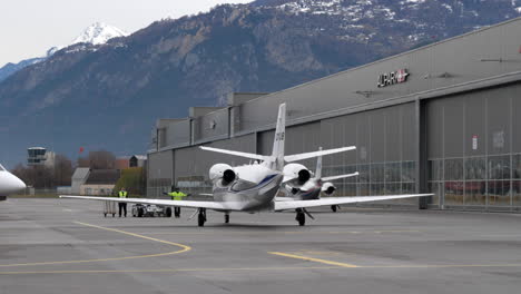 Private-jet-gets-guided-by-marshaller-in-front-of-hangar,-Sion-Airport