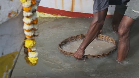 Indian-fisherman-rinsing-his-catch-of-fish-and-prawns-in-a-woven-basket-sea-water-slow-motion