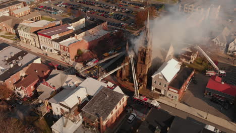 Fire-fighters-moving-into-burning-church-in-small-town,-Aerial,-Slow-Motion