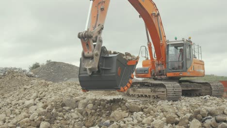 Large-bucket-on-digger-picks-up-rock-and-drops-into-conveyor-in-quarry