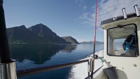 Barco-De-Viaje-Con-Cañas-De-Pescar-Pasando-Por-Crestas-En-Un-Lago-Tranquilo-En-Noruega