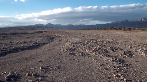 Gravel-stones-on-Death-Valley-National-Park-Mojave-Desert,-California-with-Sierra-Nevada-in-the-distance,-Aerial-pedestal-rising-shot
