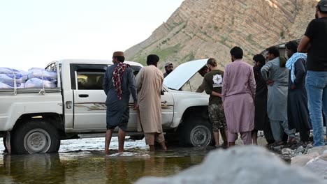 Two-people-are-repairing-the-jeep-that-carrying-the-grains-and-supplies-for-flood-victim-and-others-are-surrounding-the-jeep-in-Balochistan