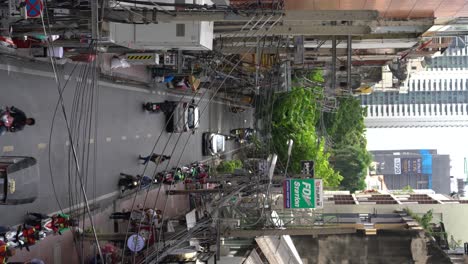 Video-Vertical:-Una-Vista-De-Los-Taxistas-De-Motocicletas-Esperando-En-La-Cola-Con-Un-Flujo-Constante-De-Tráfico-Y-Peatones-Cruzando-A-Lo-Largo-De-Soi-Saladaeng,-Bangkok,-Tailandia