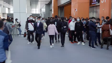 People-wearing-masks-and-walking,-looking-around-in-between-product-pavilions-at-kitchen-design-exhibition-in-China,-during-COVID-19-Pandemic