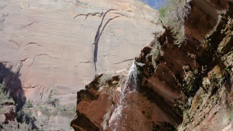 Ultra-slow-motion-shot-of-water-falling-from-rock-at-Emerald-Pool-Trail-in-Zion-National-Park,-Utah