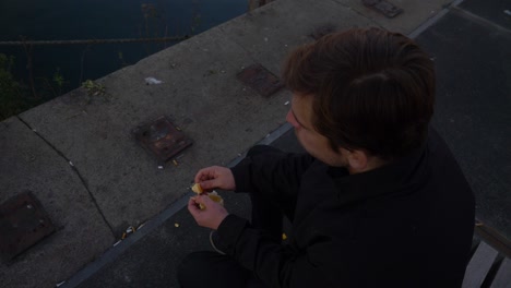 Top-down-overhead-close-up-of-a-young-man-sitting-on-a-bench-and-eating-orange-slices