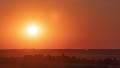 Zeitraffer-Eines-Sonnenuntergangs-Mit-Einem-Kleinen-Teil-Der-Umgebung,-Einschließlich-Verschwindender-Wolken-Und-Blendenflecken-Am-Anfang-Und-Orangefarbenen-Strahlen-Und-Windböen-Am-Ende,-Die-Der-Sonne-Folgen