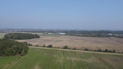 Luftaufnahme-über-Bebautem-Ackerland-Mit-Dem-Dorf-Cresnjevec,-Slowenien,-In-Der-Ferne