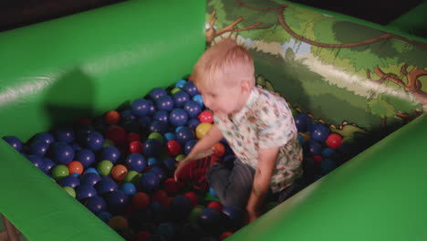 Young-Boy-Playing-in-Ball-Pit,-Smiling-and-Throwing-the-Balls-Around