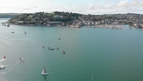 Dinghy-sailing-in-Kinsale-Harbour-on-a-summers-evening,-supported-by-powerboat-safety-boat-alongside-sailors