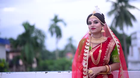 Smiling-Indian-Bengali-bride-walks-on-roof-under-cloudy-dark-sky-at-sunset