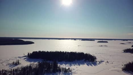 AERIAL-Nature-of-Finland-in-December,-frozen-lakes-and-clear-blue-skies