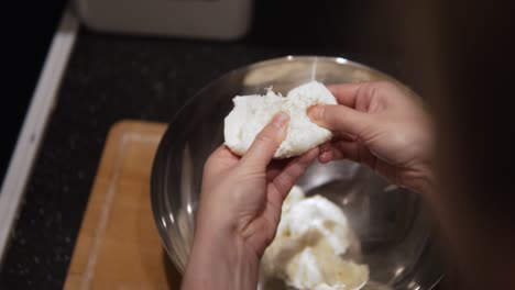 A-woman-chef-tearing-mozzarella-ball-to-smaller-pieces