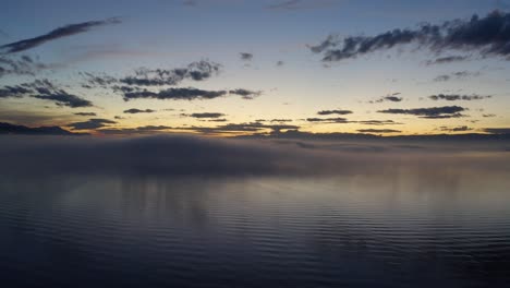 Flying-low-over-Lake-LÃ©man-with-patches-of-fog-reflecting-in-the-water-at-sunset-Vaud---Switzerland