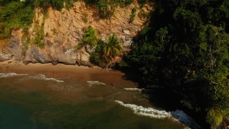 Aerial-view-of-bikini-model-at-a-cliff-side-beach-enjoying-the-waves