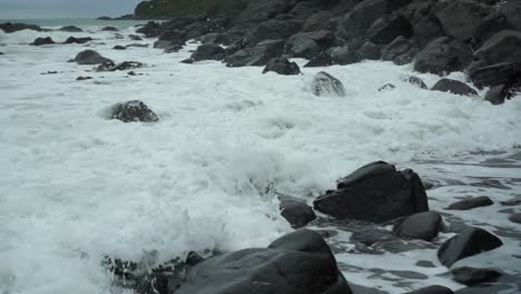 Waves-hitting-rocks-on-the-beach-in-Bluff,-New-Zealand-on-a-cloudy-day