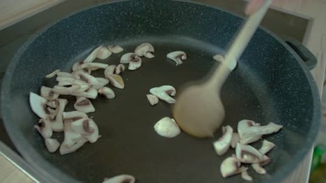 Female-stir-frying-mushrooms-in-pan