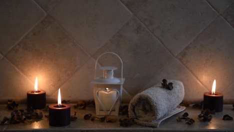 relaxing-spa-background-with-candles-with-flickering-flame,-some-wooden-petals-and-a-towel