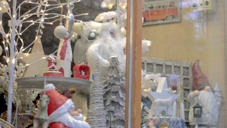 Santa-Claus,-Christmas-lights-and-decorations-behind-the-window-of-city-shop