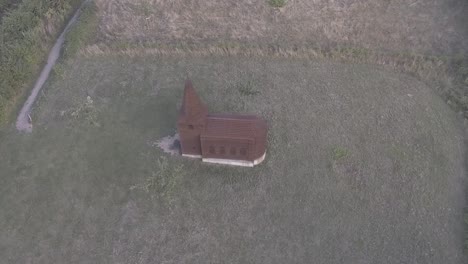 A-drone-shot-flying-to-the-side,-focusing-on-a-see-through-church-in-a-field,-keeping-it-in-the-middle