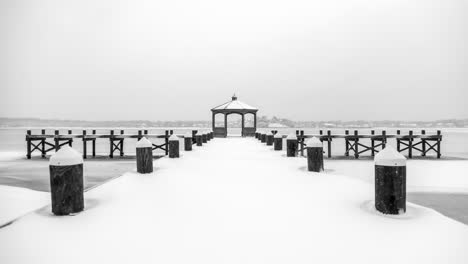 Looking-out-over-a-snow-covered-pier-at-a-large-frozen-river,-calm-and-still
