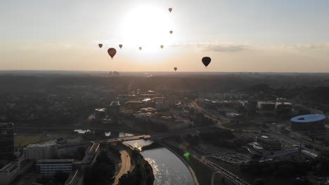 Flying-Up-and-Revealing-a-Silhouettes-of-Hot-Air-Balloons-Flying-Over-Beautiful-Green-Park-in-Vilnius