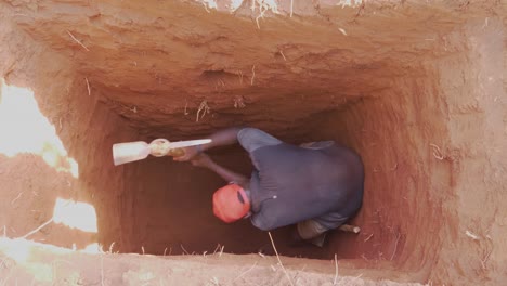 Eine-Vogelperspektive-Eines-Afrikanischen-Mannes,-Der-Tief-In-Einer-Grubenlatrine-Gräbt
