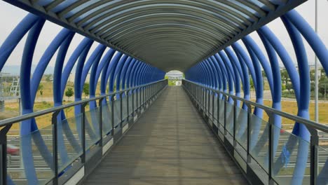 Crossing-a-bridge-over-the-highway-made-of-blue-metal-tubes-on-foot