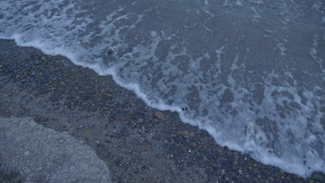Pan-of-waves-rolling-onto-the-gravel-shore