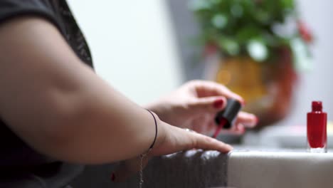 Young-attractive-girl-painting-your-nails-on-red-color-at-home