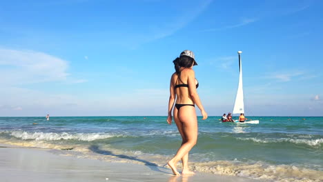 Woman-In-Black-Thong-Bathing-Suit-And-Hat-Walking-Into-The-Water-On-The-Beach-In-Mexico-During-The-Day
