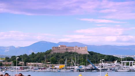 Outdoor-shot-for-the-amazing-coast-of-Antibes-with-a-castle-hill-in-the-distance-and-mountains-in-the-background-on-an-amazing-partially-cloudy-day