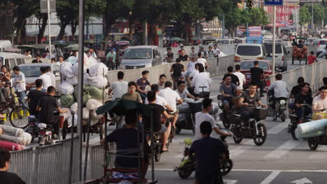 Cars,-motorbikes-and-rickshaw-heavy-loaded-with-textile-rolls-driving-in-the-street-of-textile-market-area-in-Guangzhou,-China