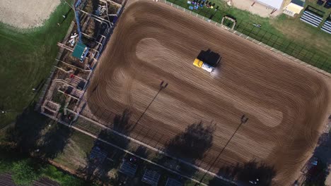 Aerial-ascend-to-very-high-angle-to-reveal-patterns-mad-by-water-truck-wetting-down-groomed-dirt-arena,-Kansas,-Missouri